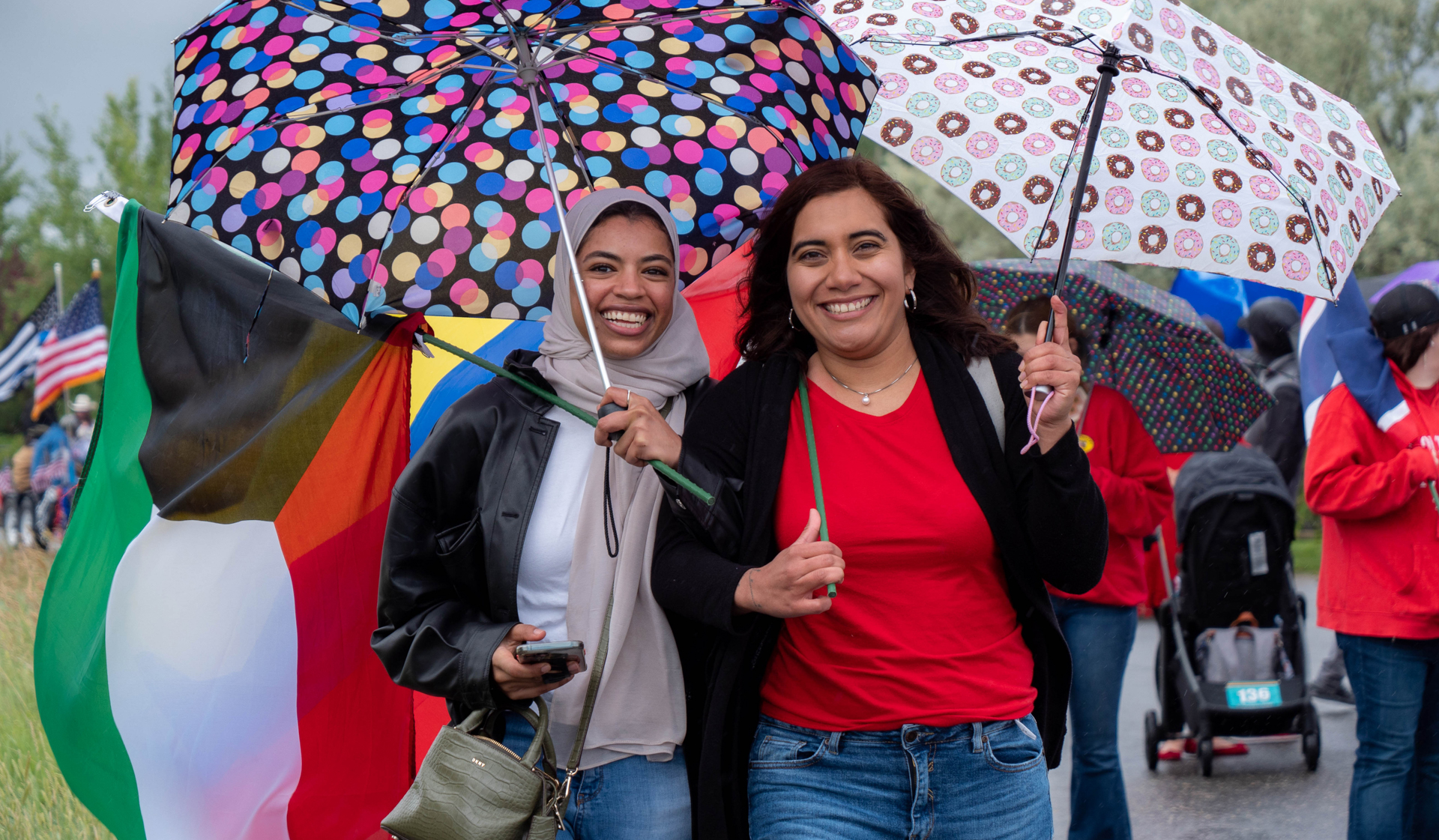 Two smiling female students holding umbrellas