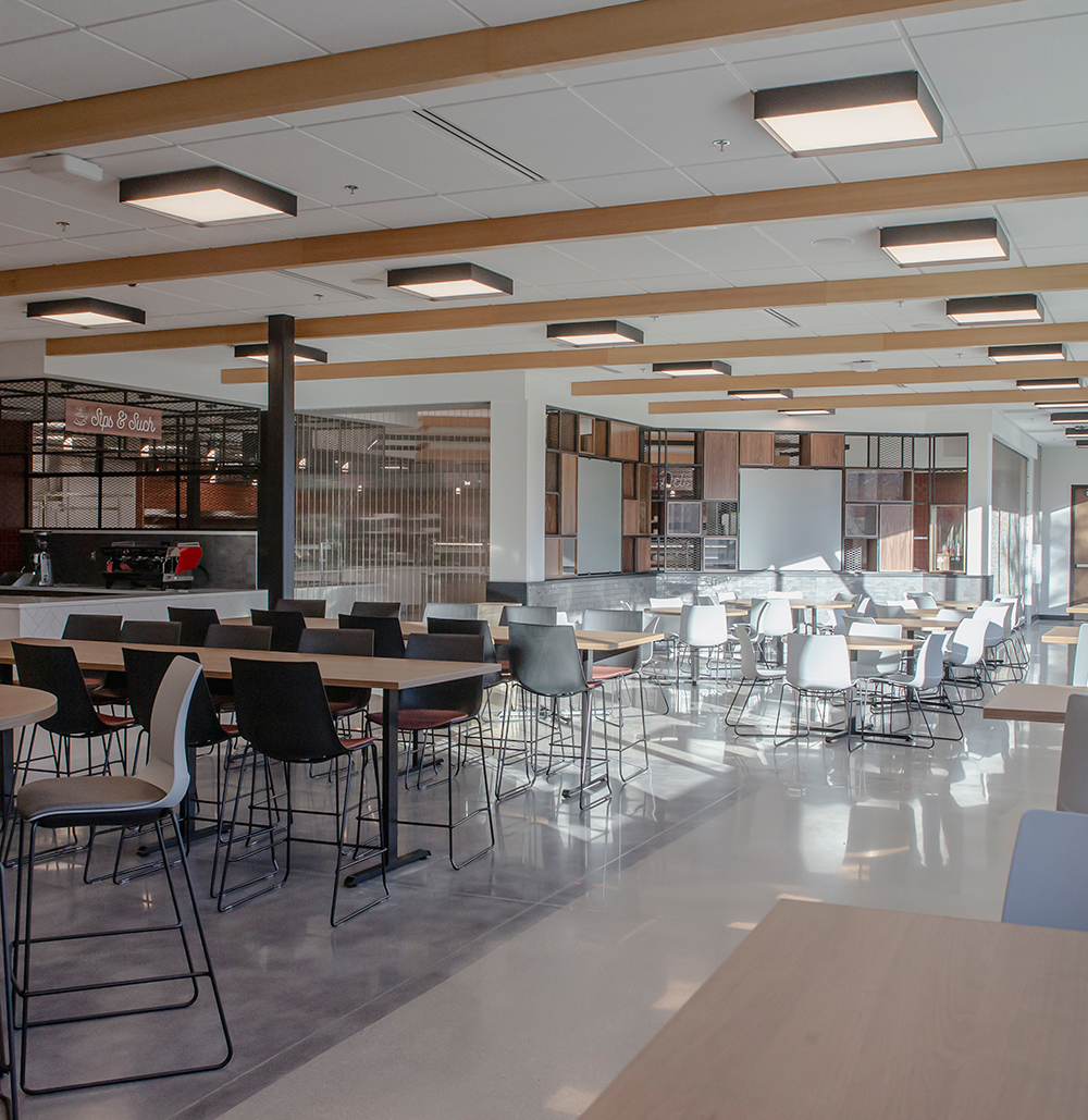 Dining area with high top tables and chairs in front of a coffee bar and serving area