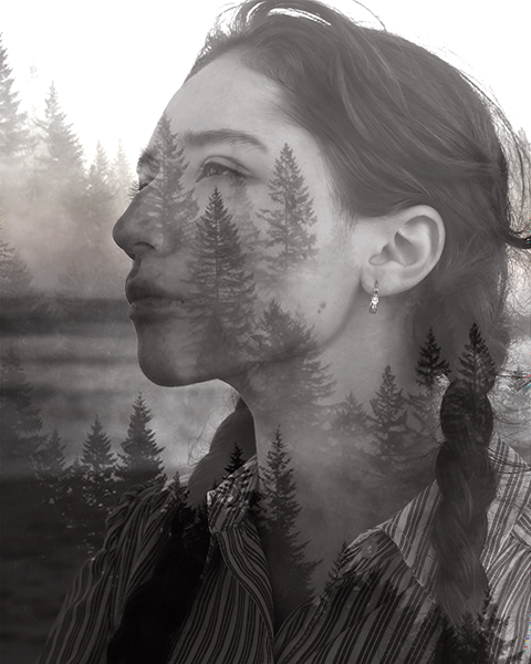 A black and white photo of a woman with long braided hair combined with trees