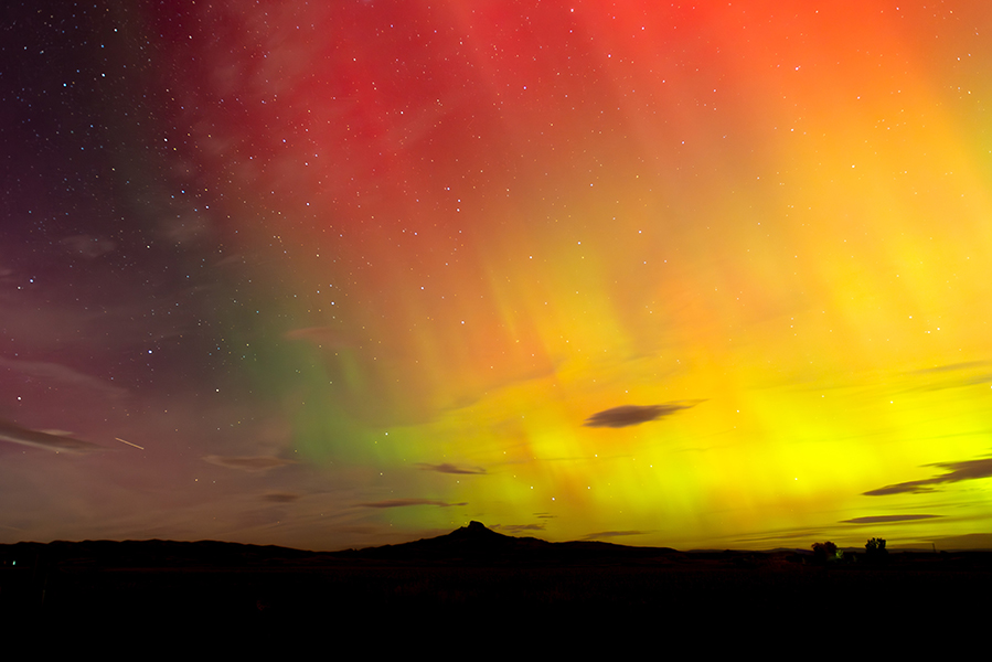 Dramatic northern lights above a distant mountain peak