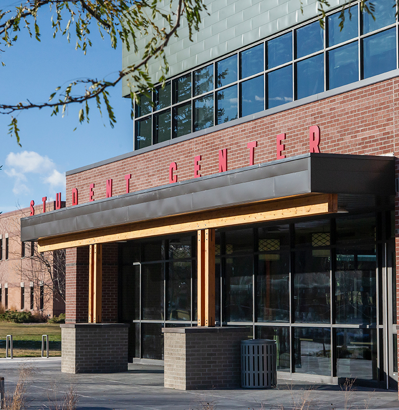 Front view of student center building with red lettering on roof overhang above front entrance with reflections off second tory windows